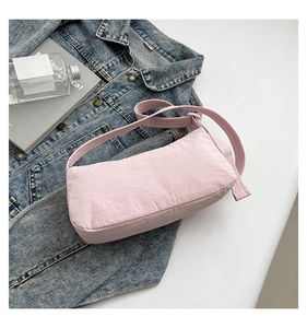 Detailed close-up of light pink nylon baguette bag with textured fabric and wide strap