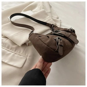 Détails de la texture du sac croissant en daim marron foncé avec boucle argentée