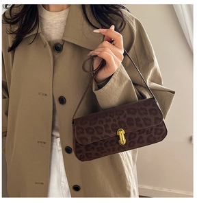 Detail of leopard print underarm bag with gold twist lock on a beige trench coat