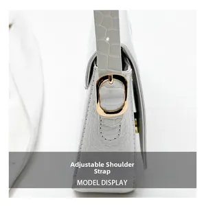 Detail showing adjustable shoulder strap with gold metal buckle on white croc-embossed bag