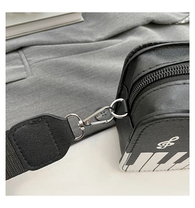 Close-up of piano keyboard print and silver metal hook on black textured leather bag