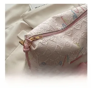 Detail of pink quilted makeup bag showing smooth golden zipper and colorful embroidery