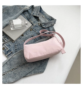 Detail view of pink nylon baguette bag on denim background with soft texture