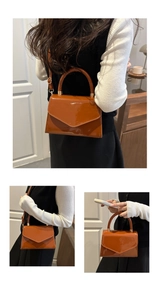 Detail of a brown patent leather crossbody bag with metallic clasp and adjustable strap