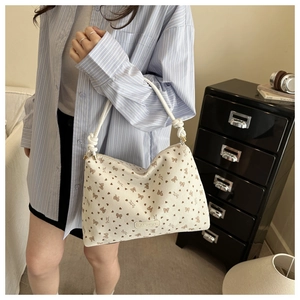 Detail of off-white corduroy tote with bow patterns and woven rope handle
