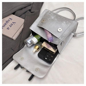 Macro shot showing internal storage of silver bow handbag with smartphone and cosmetics