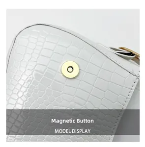 Macro shot of white crocodile embossed leather bag with golden magnetic snap closure