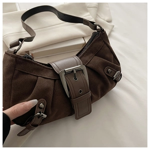 Détail d'un sac en daim marron foncé avec boucle métallique vintage et côté plissé élégant