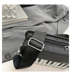 Detail of adjustable nylon strap and silver metal hardware on a piano-pattern leather bag