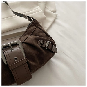 Gros plan sur un sac bandoulière en suédine marron avec boucle rétro et texture mate