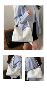Close-up of embossed texture and colorful wave embroidery on white canvas tote bag