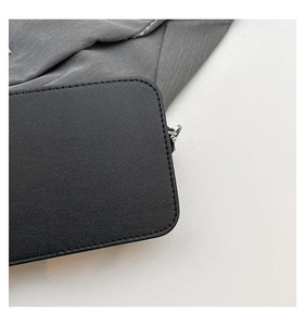 Detail of black pebbled PU leather bag with precise stitching and silver chain hardware