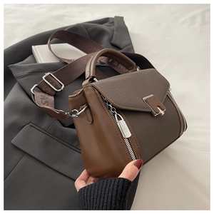 Detail of retro brown leather handbag showing mixed canvas texture and silver hardware