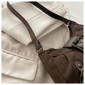 Détail du sac seau en daim marron avec fine bandoulière et texture plissée élégante