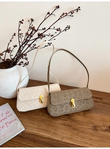 Close-up of leopard print baguette bags in beige and taupe with gold U-shaped buckles