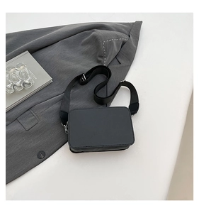 Detailed view of black PU leather box bag with adjustable wide fabric crossbody strap