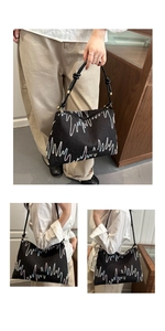 Detail view of the wave embroidery and metal ring accents on the black shoulder bag