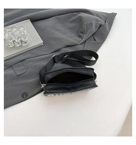 Detail of creative piano keyboard crossbody bag featuring adjustable black strap and zipper