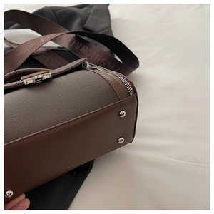 Detail of retro color-block bag with silver base studs and canvas leather texture