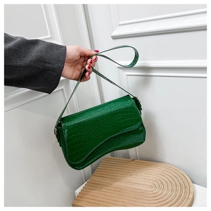 Close-up of emerald green faux leather bag with crocodile pattern and curved bottom