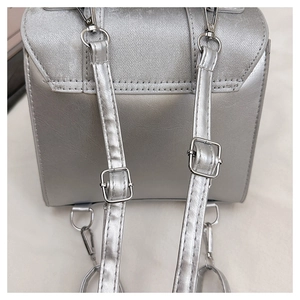 Detail of silver backpack back showing adjustable straps and metallic buckle hardware