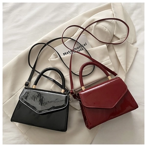 Detail of glossy patent leather mini bags in black and burgundy with V-shaped flap cover