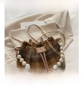 Detail of checkered bucket bag with pearl handle and metal drawstring eyelets