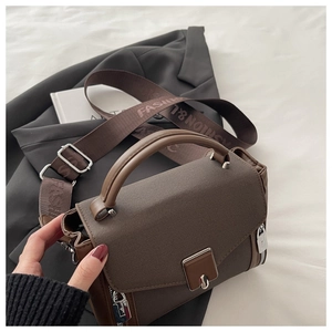 Detail of dark brown grained leather handbag with silver clasp and fashion strap