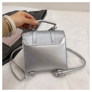 Close-up of a silver metallic bow backpack with polished mirror finish and top handle