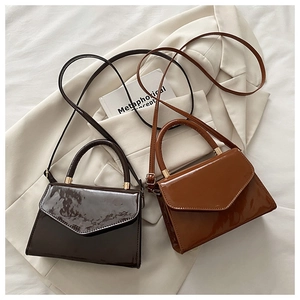 Flat lay of retro patent leather envelope bags in coffee and caramel colors on a beige blazer