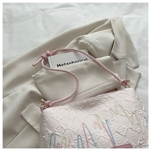 Close-up of pink textured canvas tote with colorful wavy embroidery and leather strap