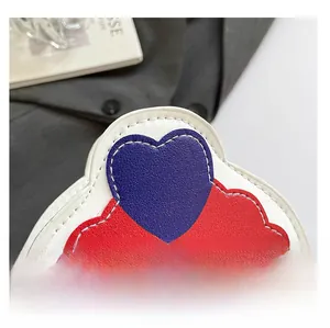 Macro detail of white lychee leather bag featuring red wave edge and blue heart pattern
