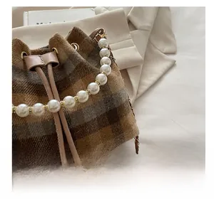 Detail of checkered tweed bucket bag featuring large pearl handle and drawstring