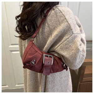 Detail of burgundy vintage underarm bag with large silver buckle and textile texture