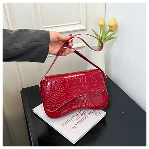 Close-up of red crocodile embossed patent leather shoulder bag with sleek flap design