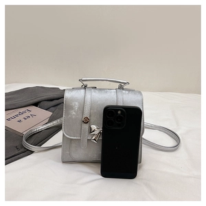 Detail of silver metallic bow handbag with buckle and handle on white background