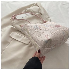 Detail of quilted canvas tote with colorful embroidery and knot shoulder strap
