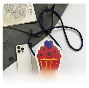Mini cupcake-shaped crossbody bag with heart detail and smartphone for size comparison