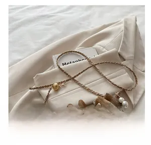 Detail showing the plaid bucket bag with pearl handle and chain strap on fabric
