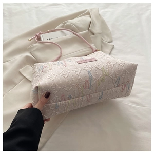 Detail of pink jacquard fabric with colorful embroidered letters and slim handles