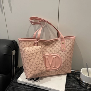 Pink monogram tote bag set with embossed M logo and matching small pouch in a lifestyle setting