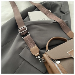 Detail of a brown PU crossbody bag with wide woven strap and FASHION & CLASSIC text