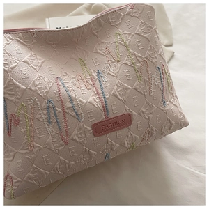 Detail of pink canvas tote with textured diamond pattern and colorful wave embroidery