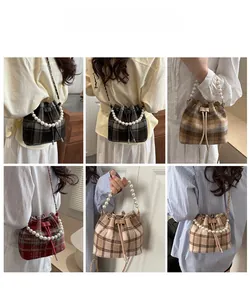 Detail view of plaid bucket bags with pearl handles and drawstring closure in six colors