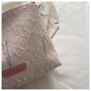 Detailed close-up of pink quilted fabric with wavy colorful embroidery and FASHION tag
