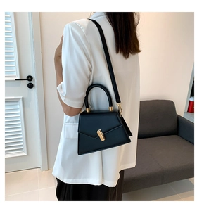 Détail d'un sac à main trapèze en cuir PU noir chic avec dorures et poignée ronde