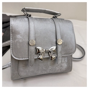 Macro shot of silver metallic texture and detailed silver bow hardware on the flap bag