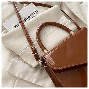 Close-up of brown patent leather mini bag with gold hardware and top handle detail