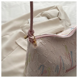 Detail of pink canvas tote with wavy embroidery on a beige blazer background