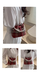 Detail view of red plaid bucket bag with pearl handle and metal chain strap